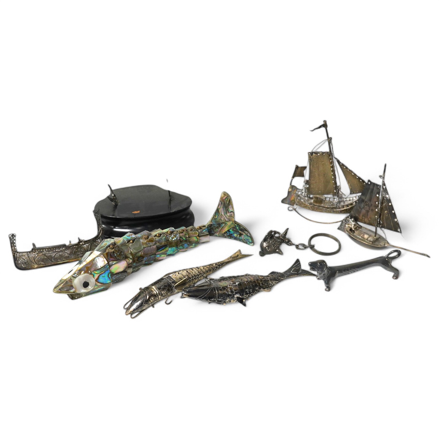 Two continental white metal reticulated fish, with hinged heads, 11.8cm, a similar paua shell mounted reticulated fish, a miniature silver model of a yacht, two other white metal model boats and two other items. Conditio